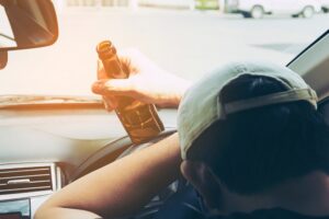 Man in vehicle holding a beer bottle