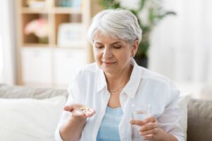 Image of senior woman taking medication with a glass of water