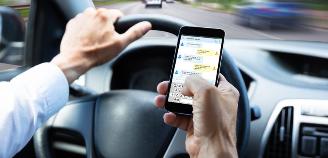 Man texting on his cell phone while driving a cae