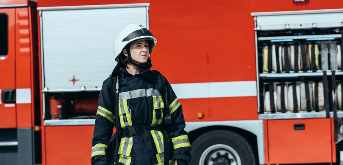 Image of a female firefighter standing in front of a fire truck