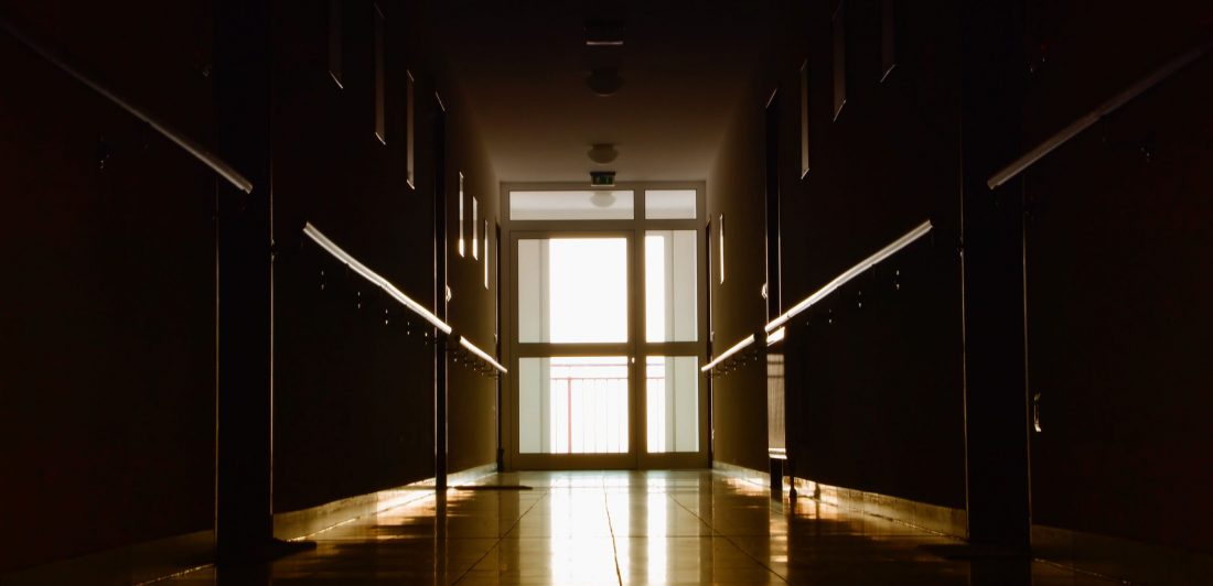 Image of a dark hallway with a brightly lit door at the end