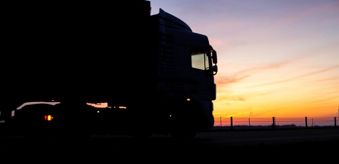 Image of a long haul truck on the road at sunset