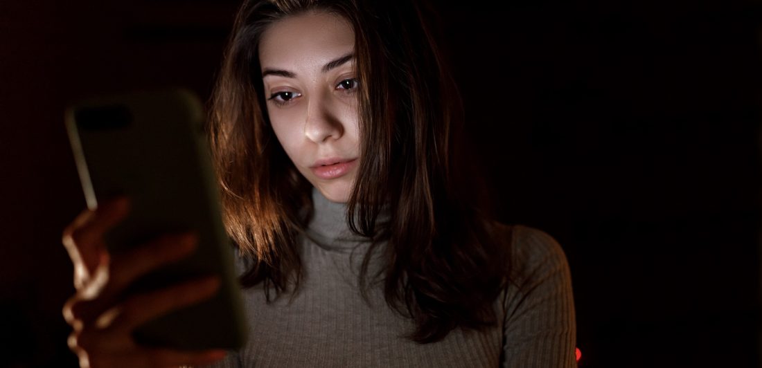 Image of woman looking at her cell phone in the dark