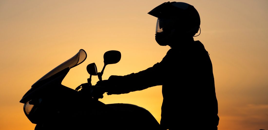 Silhouette of person on motorcycle at sunset