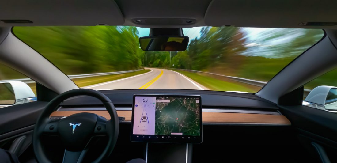 Image of person driving a Tesla on autopilot