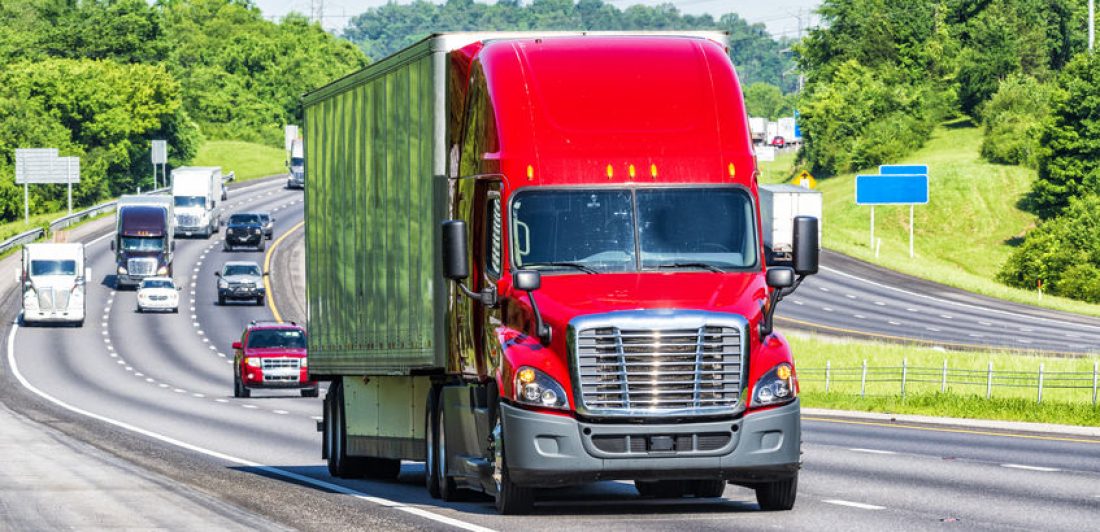 Image of a red semi on the highway with other vehicles