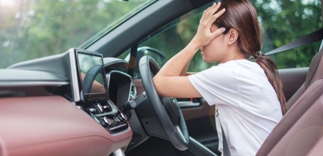 Image of woman in car with her face covered by her hands