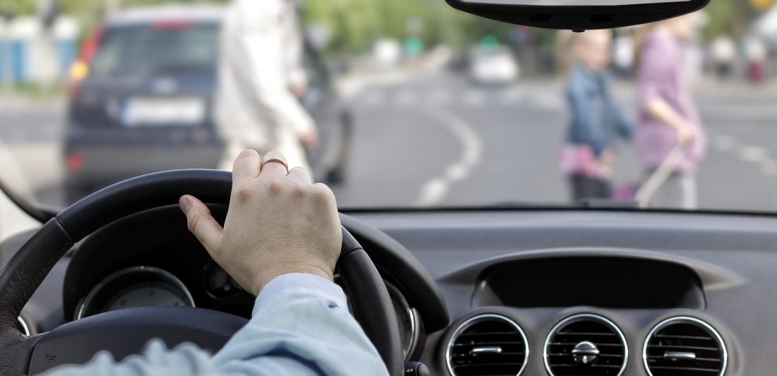 Image of person driving a car with pedestrians in the crosswalk