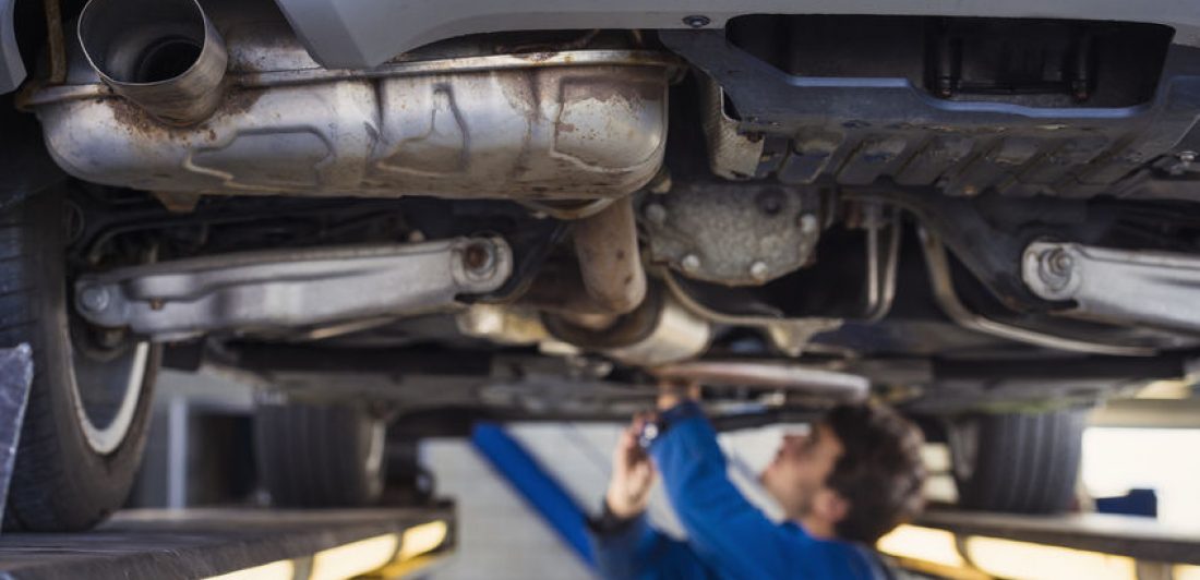 Image of man working on a car that is raised on a lift