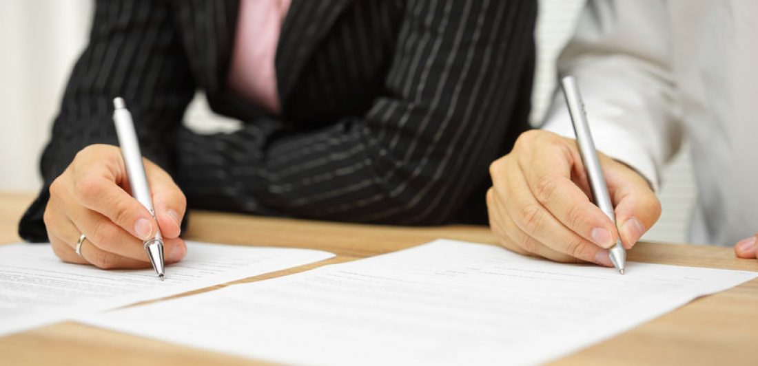 Image of two people signing paperwork