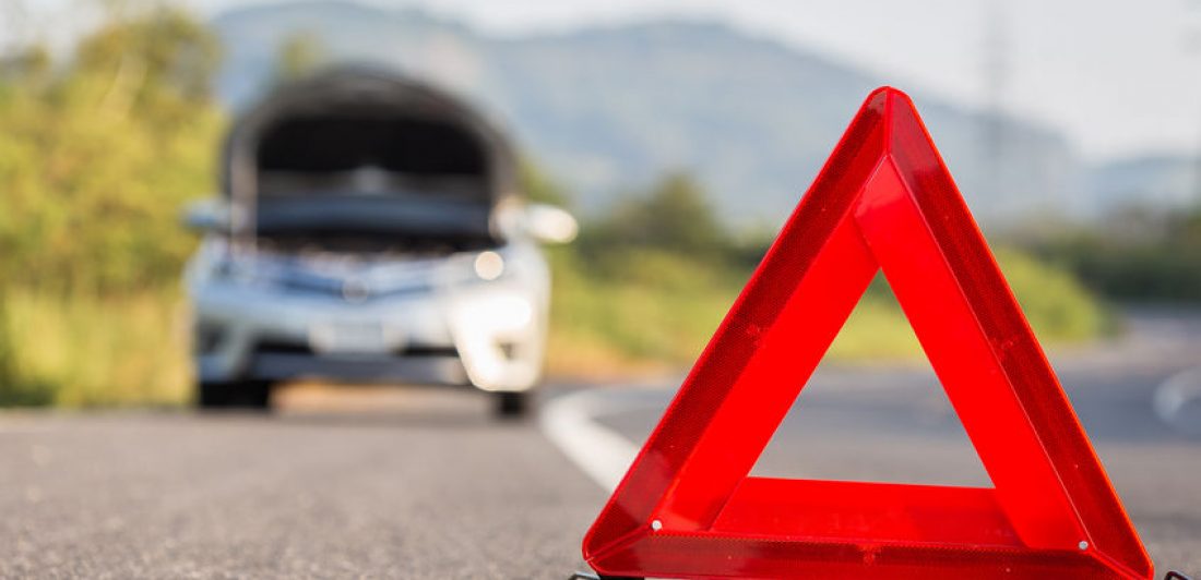 Image of vehicle broken down on the side of the road with a red emergency triangle