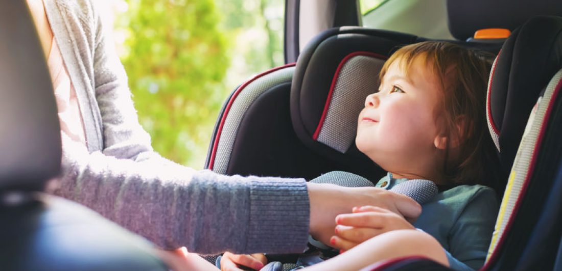 Image of happy toddler being buckled into her carseat