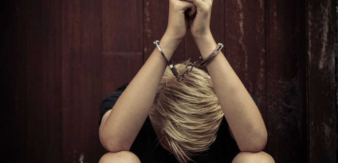 Image of young teenager in handcuffs with his head down