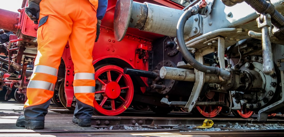 Image of a railway worker in safety gear standing by a train