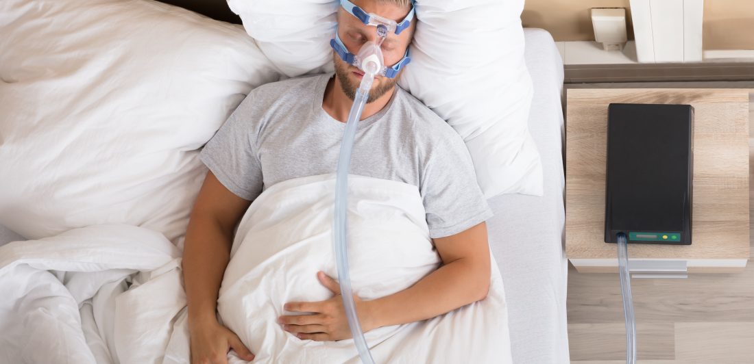 Image of a man sleeping with a CPAP machine