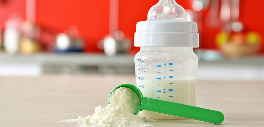 Image of a baby bottle on a counter with a scoop of baby formula