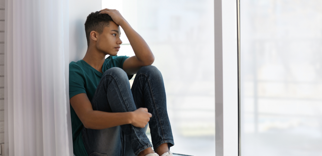 Image of person looking sad, sitting by a window