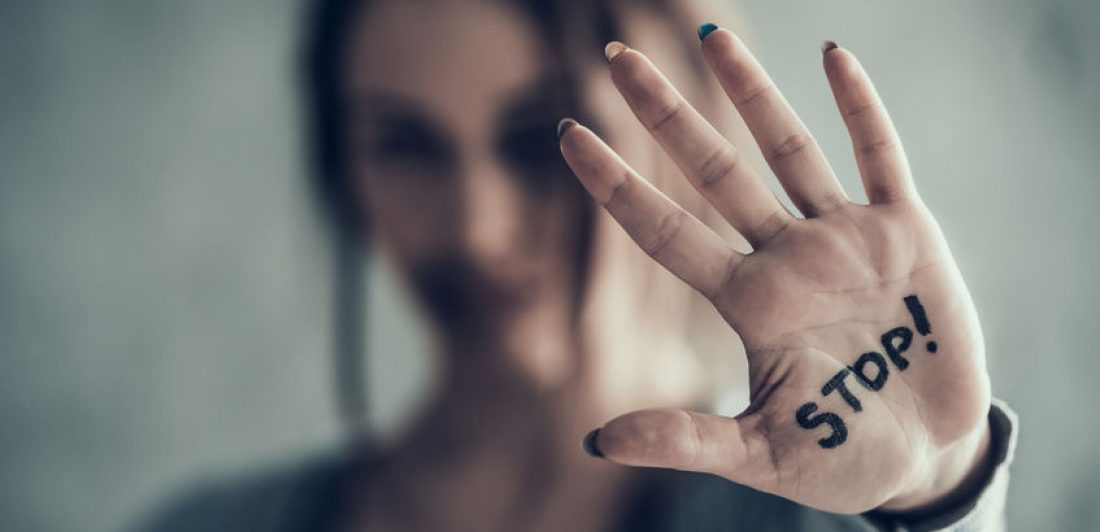 Image of woman holding her hand up with the word stop! written on her palm