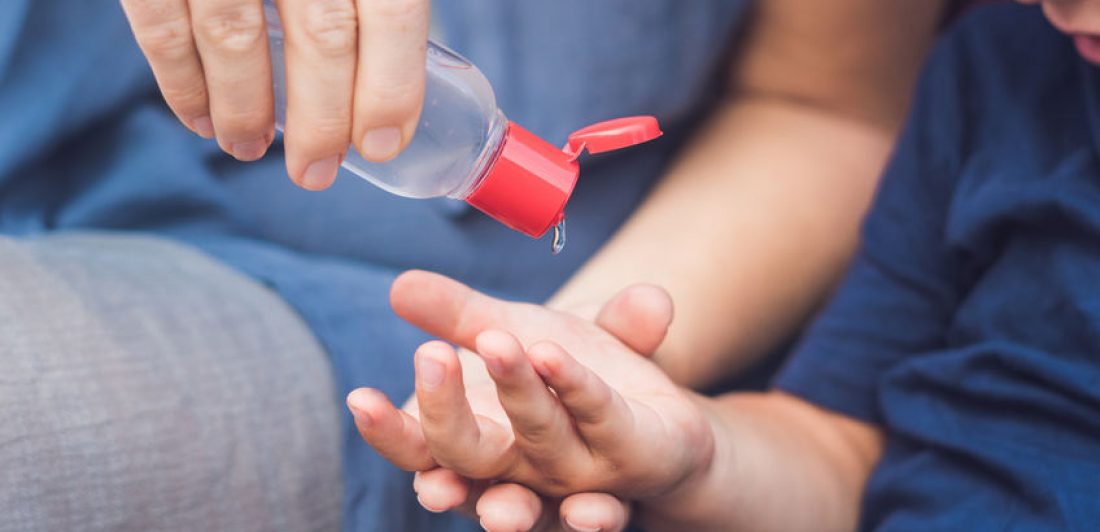 Image of person pouring hand sanitizer in small child's hand