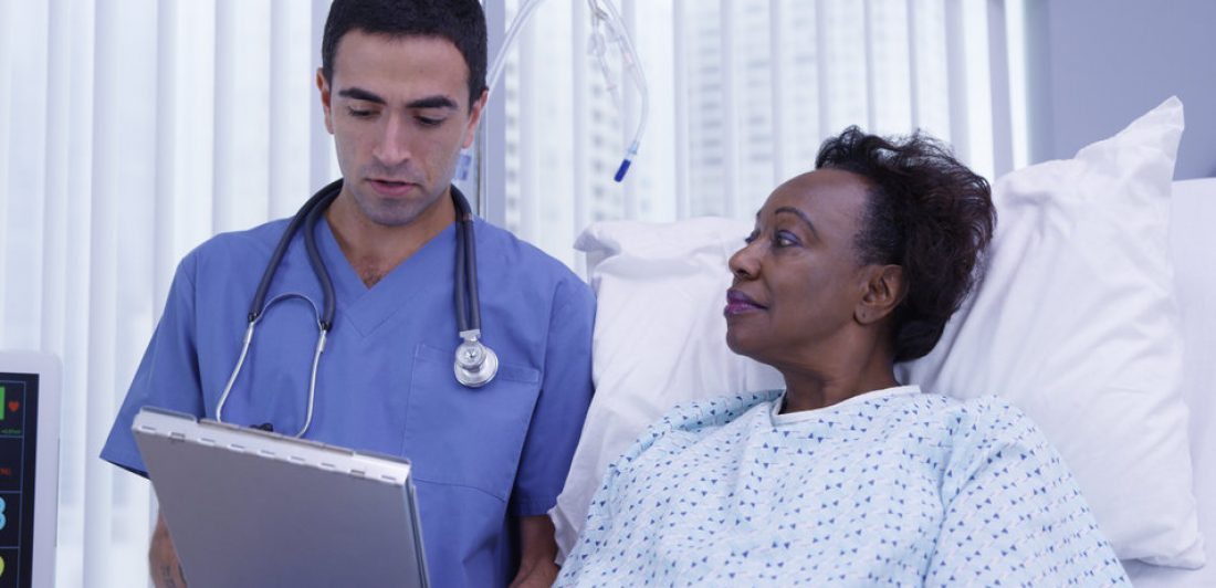 Image of doctor standing bedside with senior patient