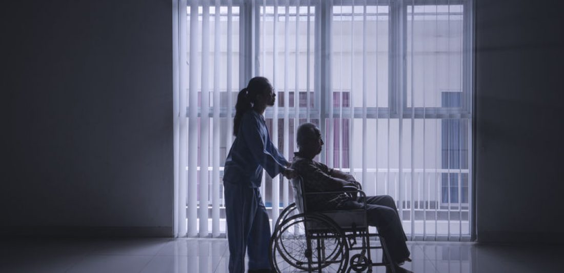 Image depicting healthcare worker pushing elderly man in a wheelchair