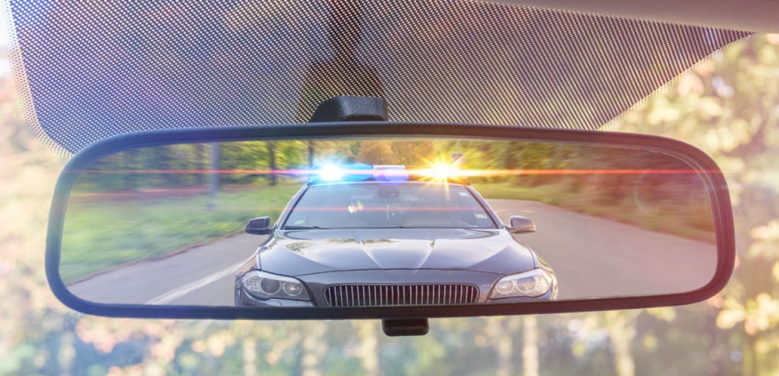 Image of police car with lights on in rearview mirror