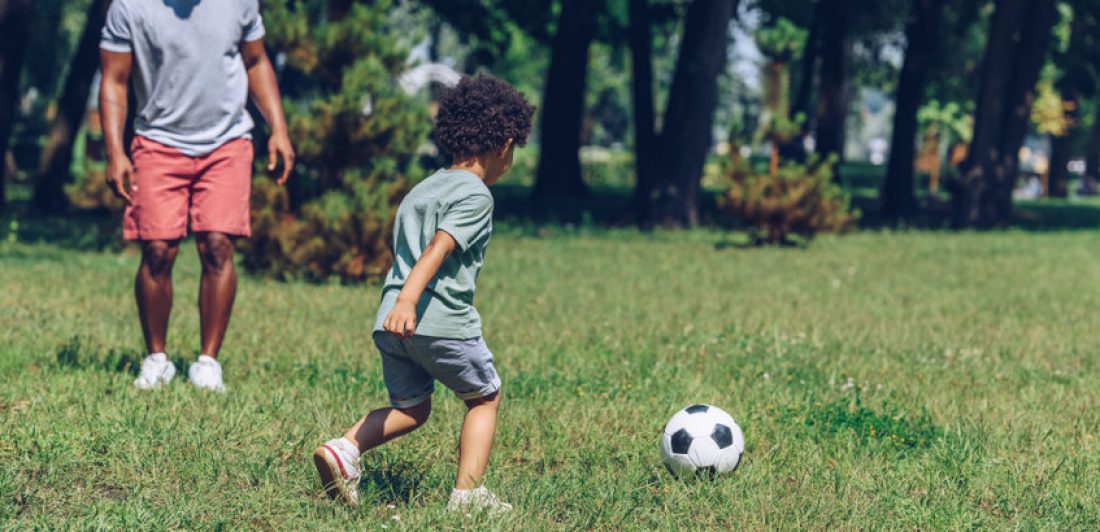 Image of man playing soccer with a young boy