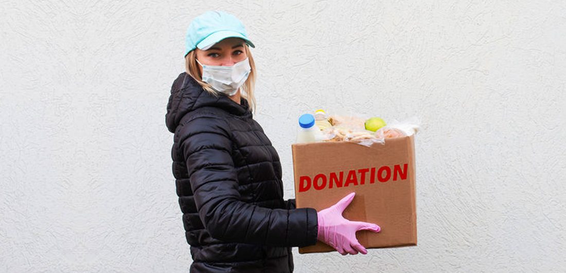 Image of a woman in a mask with gloves carrying a donations box