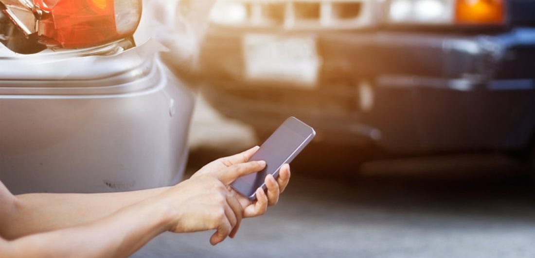 Image depicting a man using his cell phone at a car accident