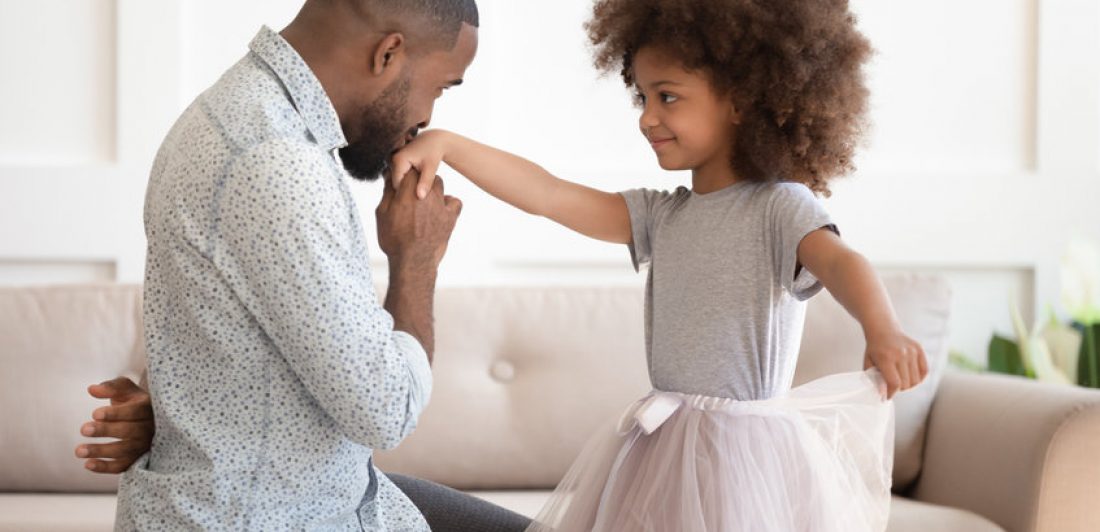 Image of dad kissing the hand of his daughter wearing a tutu