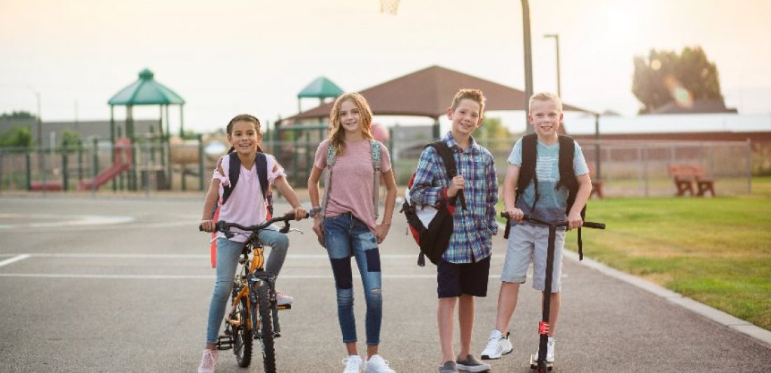 Image of kids on scooters and bikes at a playground