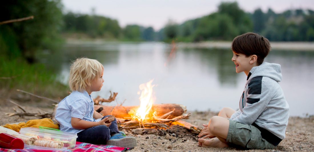 Image of two kids having a picnic near a campfire