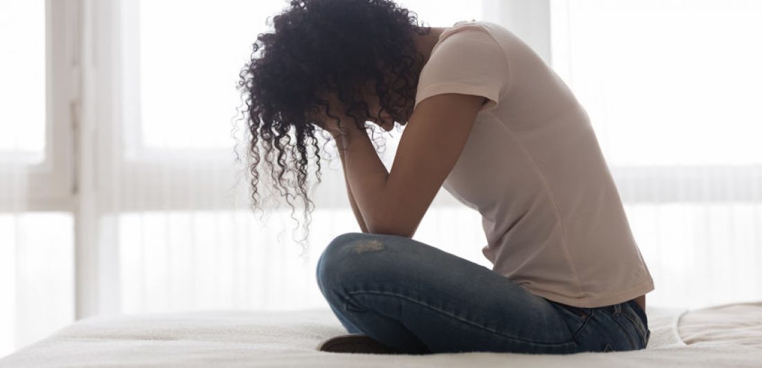 Image of woman sitting on a bed with her face in her hands