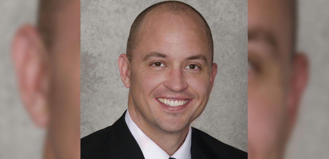 Image of man with black suite, white button up shirt, and black tie