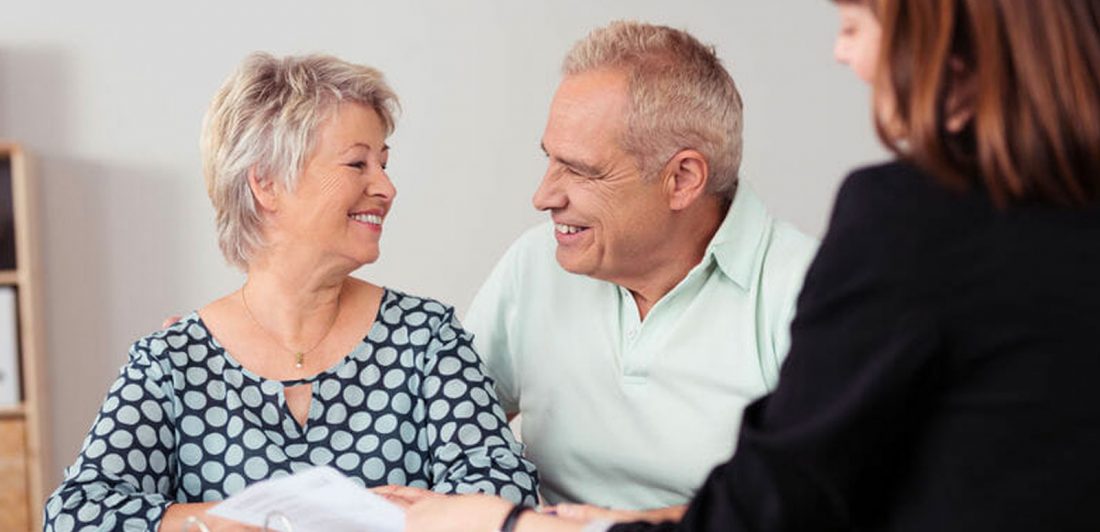 Image of happy senior couple with woman looking at paperwork