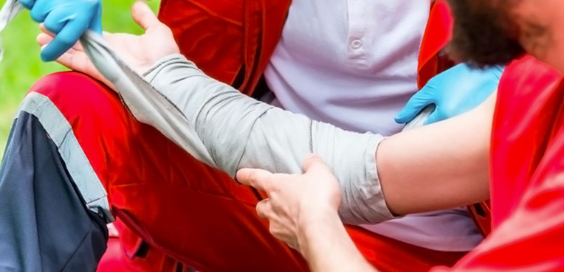 Image of a team medical professional wrapping the arm of a football player on the field