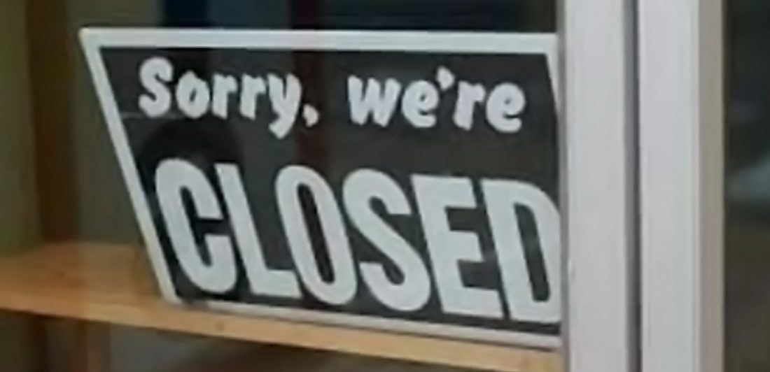 Image of a sorry we're closed sign in a store window