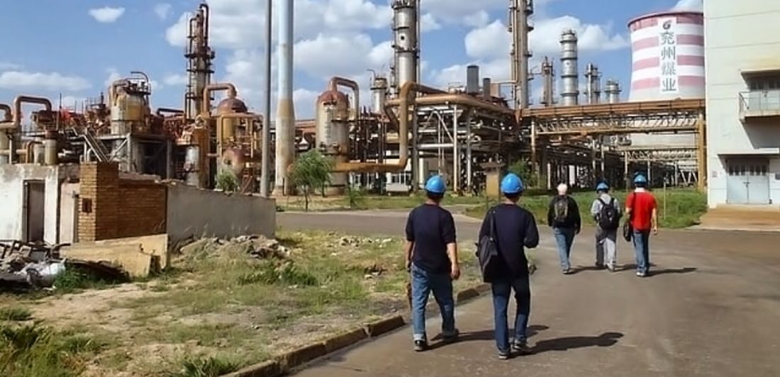 Image of workers in safety helmets walking into a chemical plant