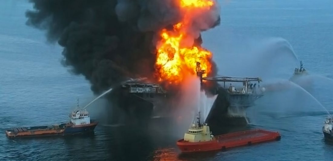 Image of large fire at an offshore oil rig being put out by boats spraying water