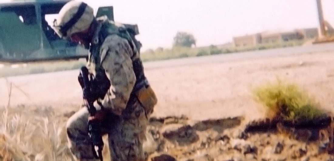 Image of soldier in fatigues with a gun in a dirt field