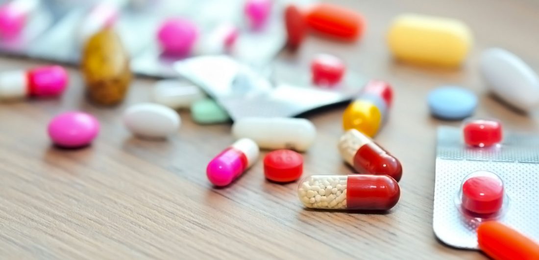 Image of various colorful pills in blister packs and loose on the table