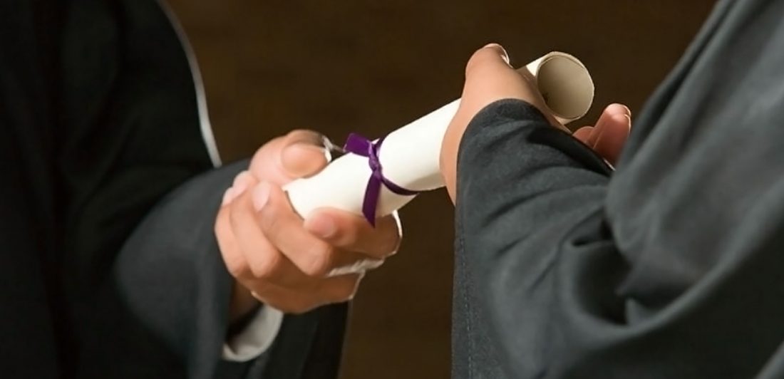 Image of a person handing a diploma to a graduate