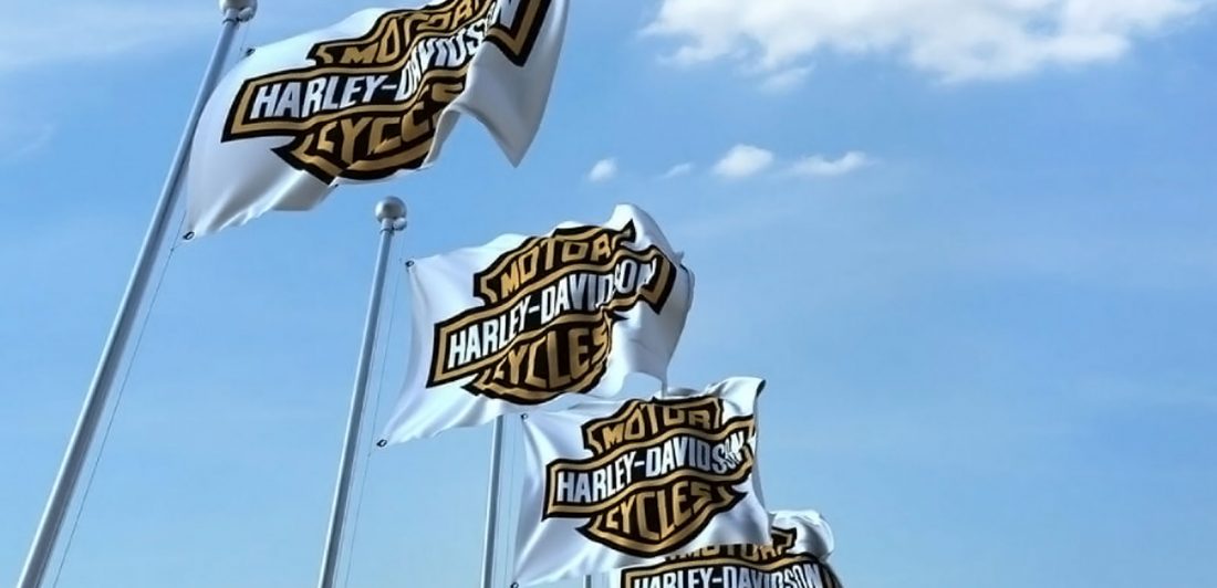 Image of Harley Davidson flags set against a blue sky with white clouds