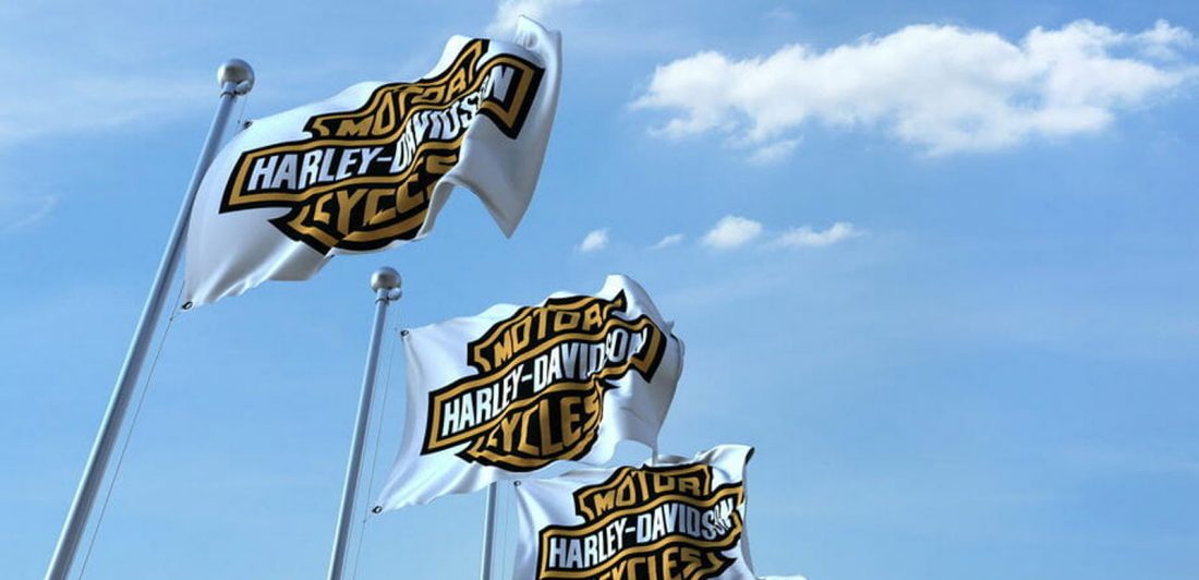 Image of Harley Davidson flags set against a blue sky with white clouds