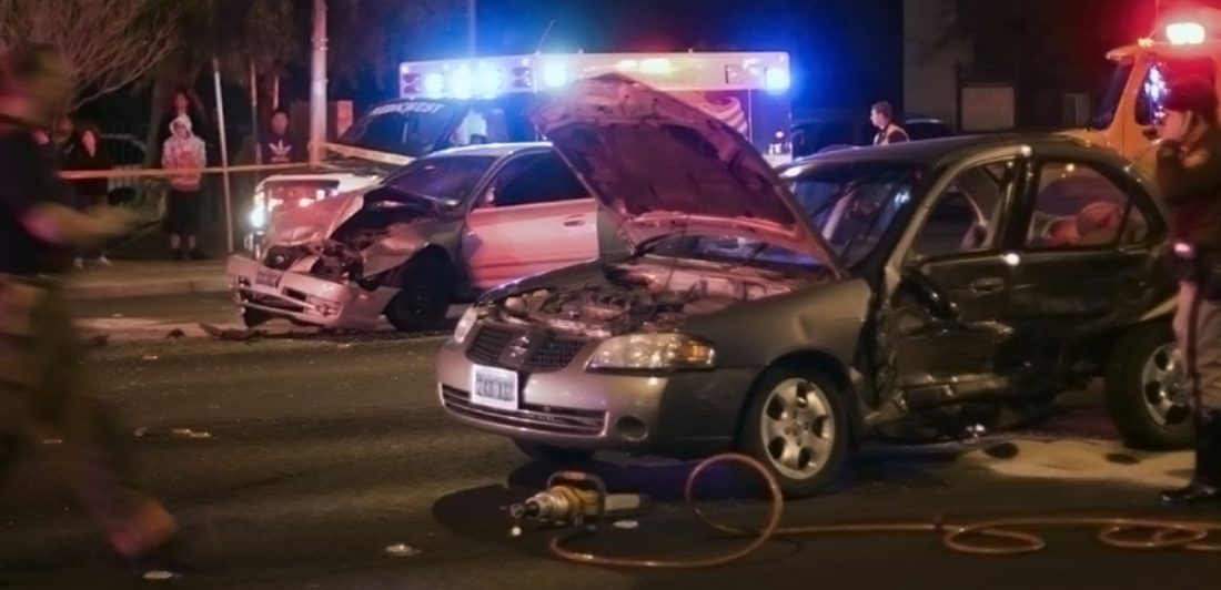 Image of a multi-car accident at night with onlookers and emergency personel