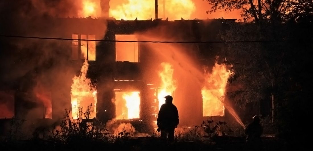 Image of man standing in front of a large structure fire