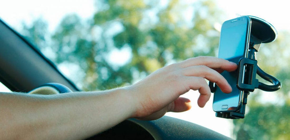 Image of person using their smart phone that is mounted on their window shield