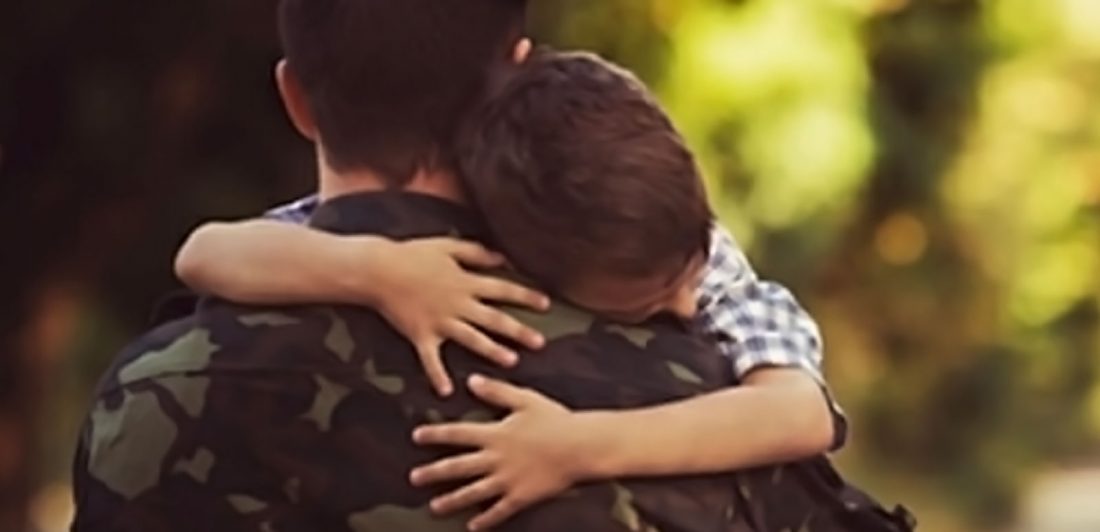 Image of child hugging man in military uniform