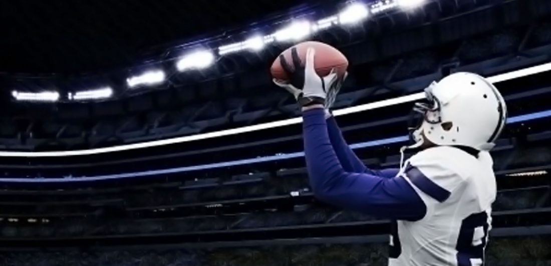 Image of Dallas Cowboy football player catching a football on the field with stadium lights in the background