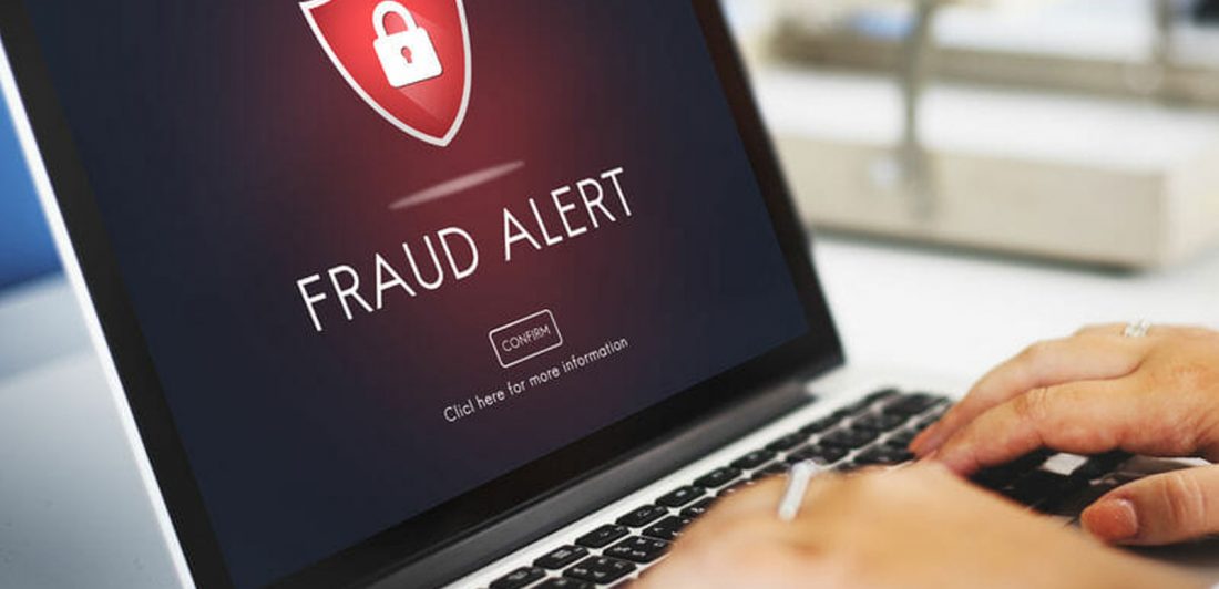 Image of a person on a laptop with Fraud Alert displayed on the screen